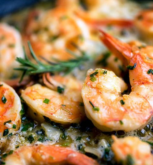 Close image of jumbo shrimp being sauteed in a pan with oregano, chive, rosemary, garlic and paprica creating Shrimp Scampi